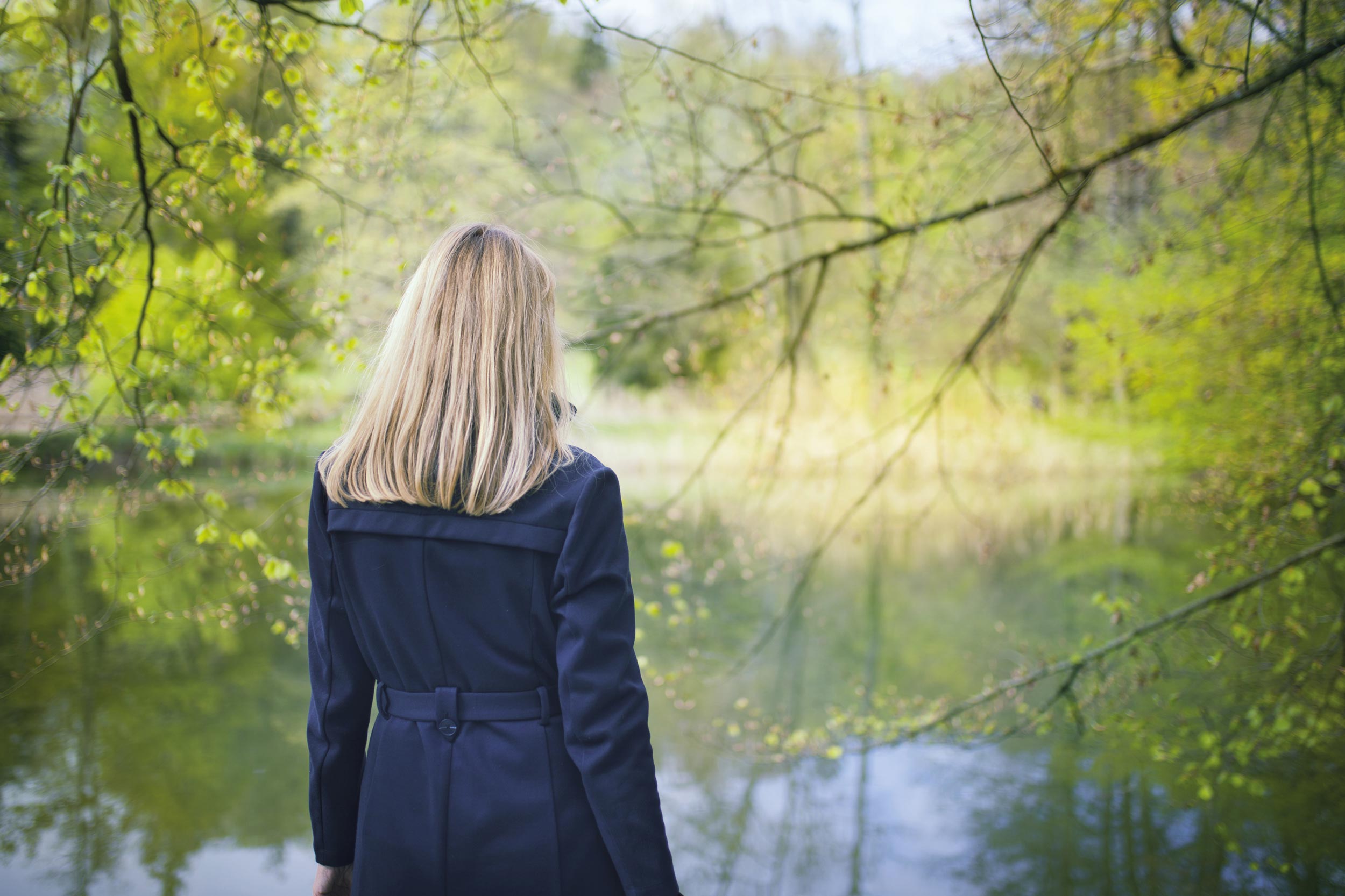 Stock foto af kvinde med ryggen til, stående ved skovsø