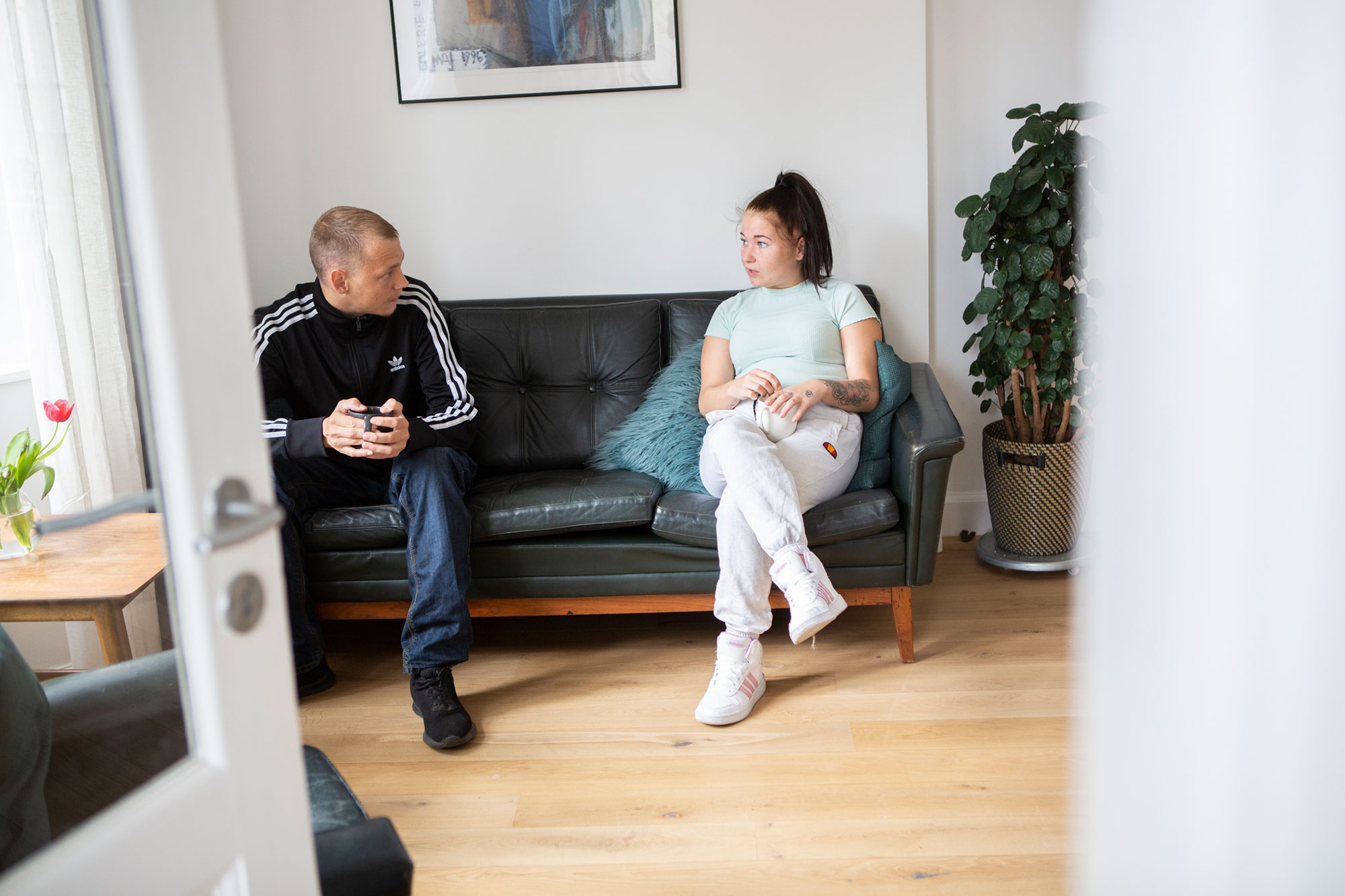 Ung mand og ung kvinde taler i sofa