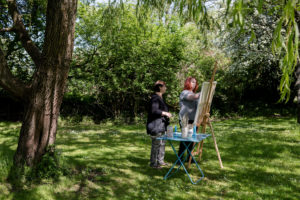Kvinde maler kunstværk i en have